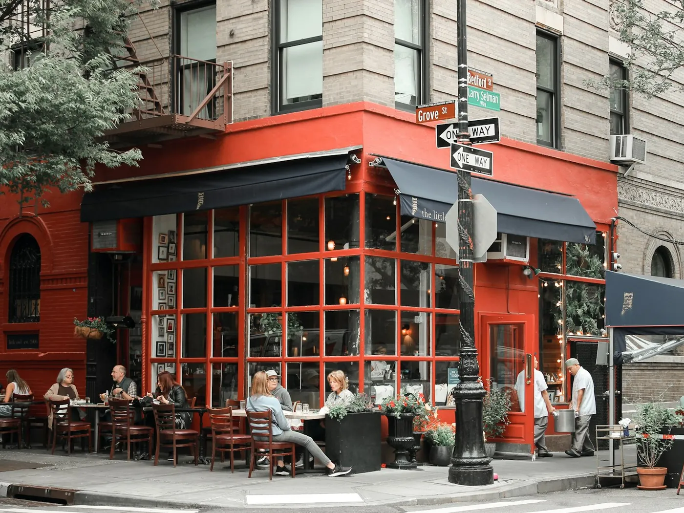 Guests at sidewalk tables outside a lively West Village restaurant.